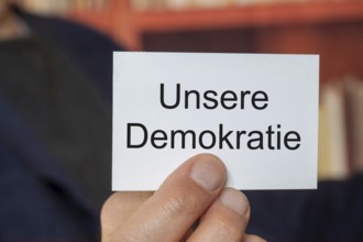 Man showing a business card with (added text) OUR DEMOCRACY (symbolic image)