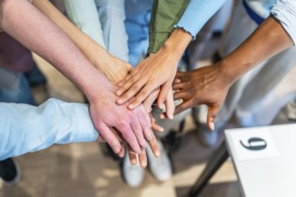 Coworkers stacking hands together, showing unity, teamwork and collaboration in the office