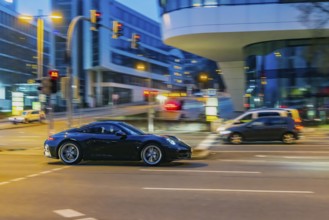 Porsche at night in front of urban surroundings with modern architecture, pull-along. Stuttgart,
