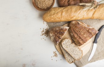 Sliced bread with different kinds of fresh baked bread on a white wooden background. top view, flat