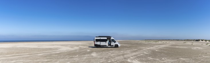 Ringby, Denmark: 31 May, 2021: panorama of a gray camper van parked on an endless white sand beach