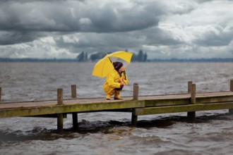 Young woman on a jetty waiting for better weather, Steinhuder Meer, Wunstorf, Lower Saxony, Germany