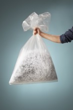 Man holding a transparent plastic bag with shredded paper