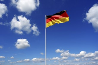 Flag of Germany fluttering in the blue sky with cumulus clouds
