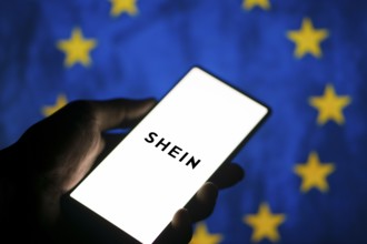 Smartphone with website of fashion e-commerce company Shein in front of business logo. Focus on