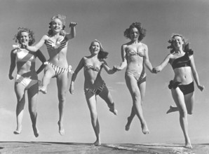 1940s summer. A group of young women in their bikinis are happy on this summer's day, jumping of
