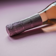 Bottle of rose champagne wine in minimal composition on pink background with copy space. Natural