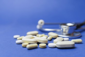 Stethoscope with pills on a blue background with a large space for text