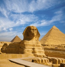 Full profile of Great Sphinx including pyramids of Menkaure and Khafre in the background on a clear