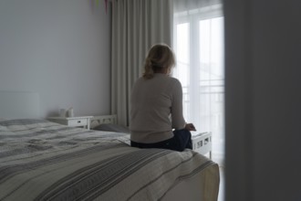 Mature woman sitting alone in the room, sad depressed person. Back view. mental health