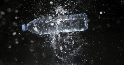 Bottle of Water falling on Water against Black Background