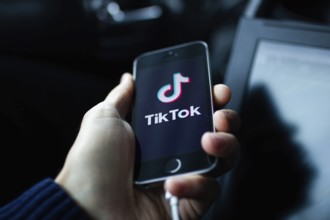 Hand holding a smartphone displaying the TikTok app logo on its screen