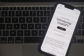 OpenAI software ChatGPT application on a mobile phone above a computer keyboard