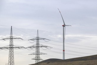 High-voltage pylons with wind turbine in german industrial landscape