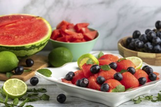 Bowl with sliced watermelon, grapes and limes in front of Ingredients