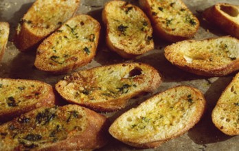 Baguette toasts, baked in the oven, with garlic butter and herbs, homemade, on a platter, top view