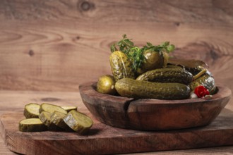 Pickled cucumbers in a wooden bowl with herbs and spices, close-up, rustic style
