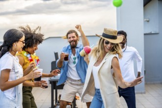Cheerful multi ethnic friends dancing joyfully and sipping cocktails while celebrating together at