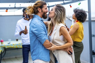 Happy couple embracing and sharing joyful moments with friends while sipping drinks at a lively