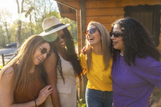 Four diverse women wearing sunglasses and casual clothes are enjoying a sunny day in nature,
