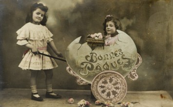 Child sitting in large egg, 1930s, Two girls in a vintage Easter photo with flowers and decoration,