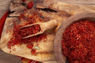Spice saffron threads, in a wooden bowl, on a wooden table, top view, close-up