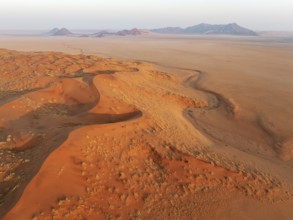 Sand dunes and isolated mountain ridges at the edge of the Namib Desert. Aerial view. Drone shot.