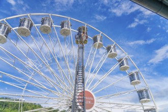 View of a high Ferris wheel with many baskets in front of a cloudy blue sky, fire brigade exercise