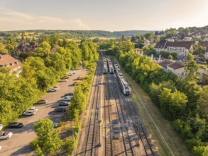 Aerial view shows railway tracks next to a car park and residential building, sunny summer