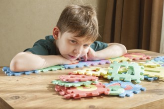 Child assembling colorful puzzle pieces on a wooden table in a bright indoor space during the day