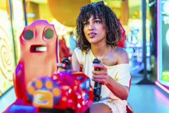 Young woman enjoying a car racing arcade game, holding the steering wheel and focused on the screen