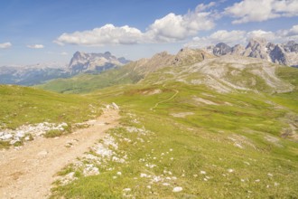 A winding path through green countryside with spectacular mountain panoramas and skies, hike to the