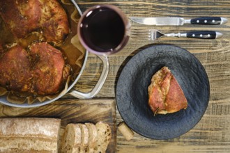 Overhead view of roasted meatin a plate and baking pan served with freshly sliced bread and a glass