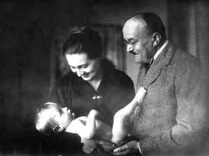 Parents with baby, 1930s, A couple smiling at a naked baby in their arms, Historical photo