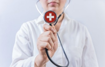 Female doctor holding stethoscope with Switzerland flag. National health system of Switzerland