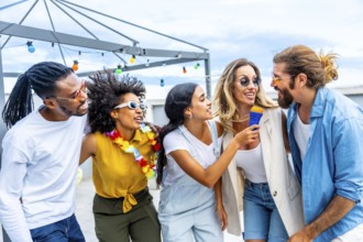 Five cheerful friends singing karaoke, holding a microphone and enjoying a rooftop party during