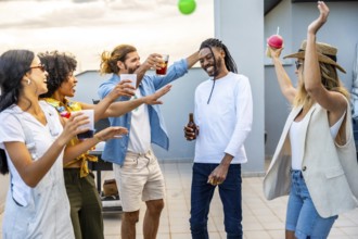 Cheerful young people enjoying drinks and dancing joyfully at a vibrant rooftop party, creating