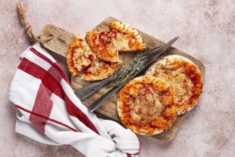 Four pizzetta Margaritas, on a cutting board, on a light gray surface, top view