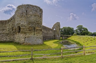Wall and moat of Pevensey Castle, a Norman castle, in the village of Pevensey, Sussex, England,