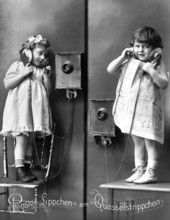 2 girls old telephone chair, Two children telephoning with wall telephones in old-fashioned