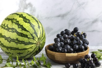 Watermelon with a bowl of grapes and mint in a bright setting