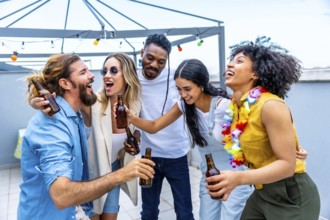 Cheerful multi ethnic friends are toasting with bottles of beer, laughing and having fun at a