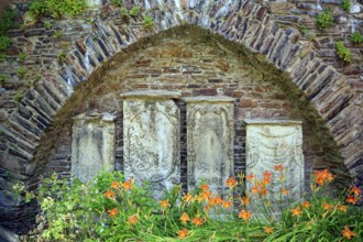 Remains of the town wall behind St Nicholas' Church with the gravestones of former priests of the
