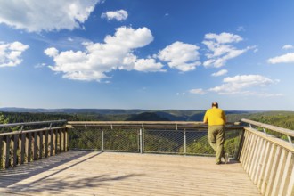 Man on the Ellbachseeblick viewing platform with a view over the wooded hills around Baiersbronn,