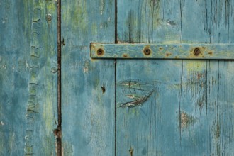 Weathered green wooden door with rusty metal accents in rustic style, background, texture,