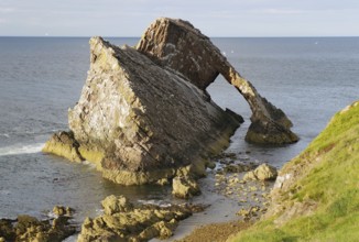 Large rock formation in a calm sea illuminated by the setting sun, Remarkable rock formation