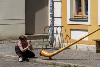 Young woman photographing an alphorn, Potsdam, Brandenburg, Germany