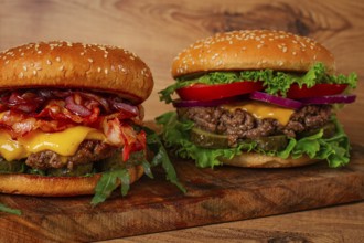 Two burgers with beef patty, fried bacon, cheddar cheese, tomatoes, homemade, no people