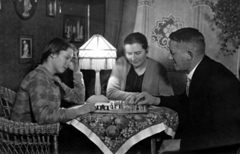 1920 Halma game, family playing chess in a cosy living room, historical photo