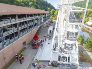 Fire engines and workers next to a Ferris wheel in an urban environment, fire brigade exercise for
